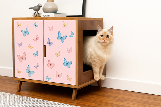 Chat crème sortant d’un meuble à litière rose avec motifs papillons – Litière Pacha
